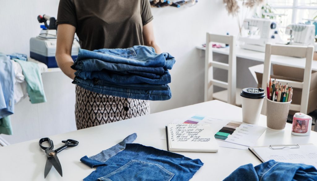 Reuse, repair, upcycle. Sustainable fashion, Circular economy. Denim upcycling ideas, repair and using old jeans. Close-up of old denim jeans fabric stack in Sewing studio.